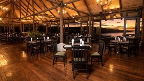 A spacious indoor dining area with wooden flooring and tables set for guests. - Casa de Palmas -Modern Villa in 4 Star Beach Resort Short Walk to Playa Hermosa! (Playa Hermosa)