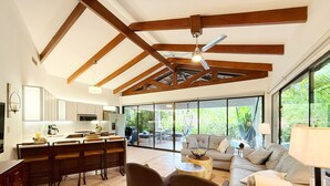 A spacious living area with a kitchen, large windows, and a ceiling fan. - Casa de Palmas -Modern Villa in 4 Star Beach Resort Short Walk to Playa Hermosa! (Playa Hermosa)