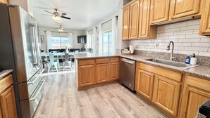 A modern kitchen with wooden cabinets, a granite countertop, and a built-in dishwasher.