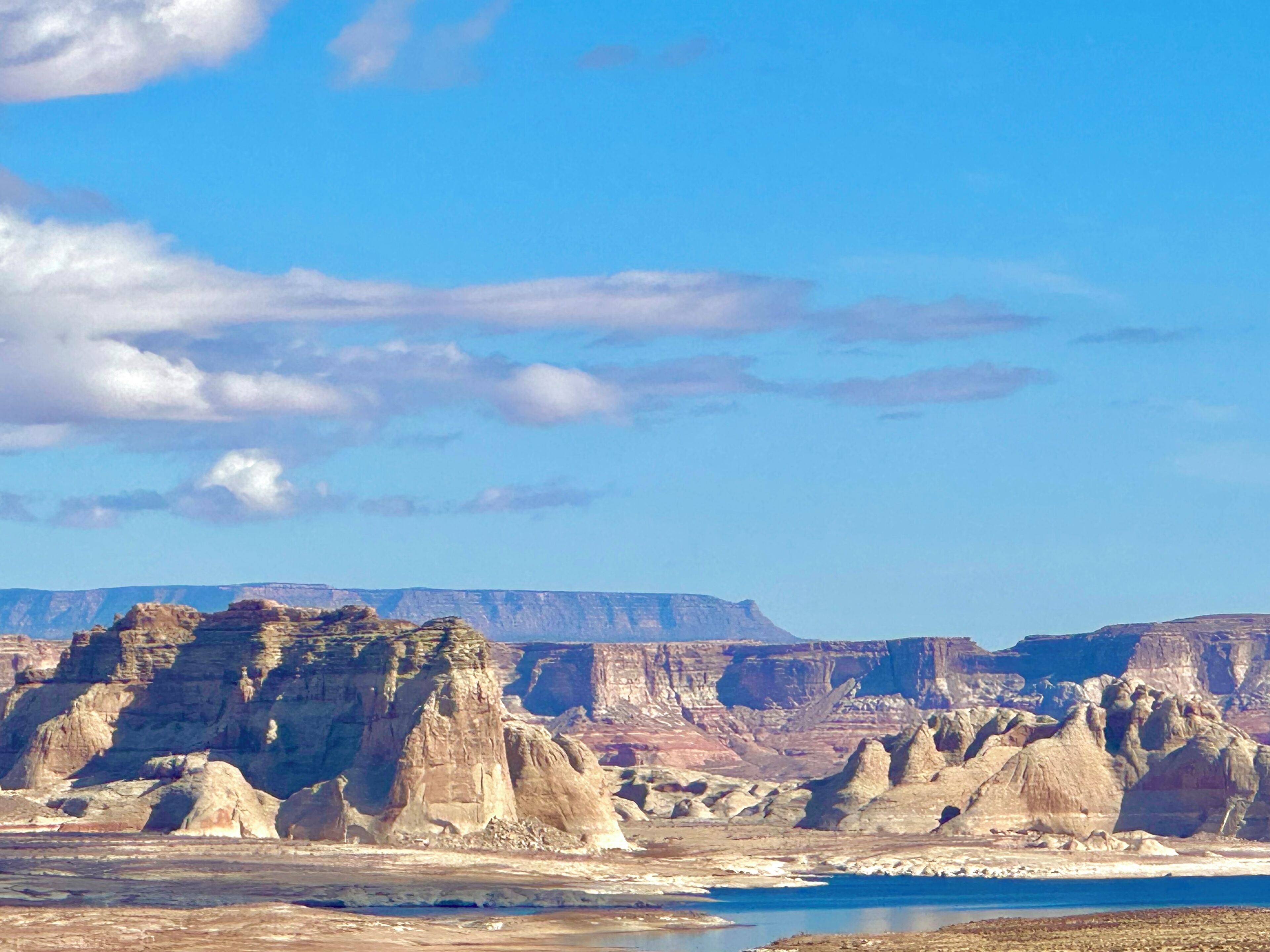 A vast landscape with rugged, layered rock formations and a clear blue sky.
