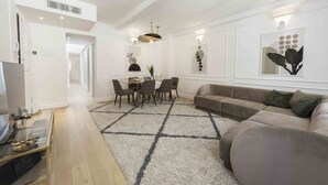A modern living room with a sofa, a dining table with chairs, and artwork on the walls.
