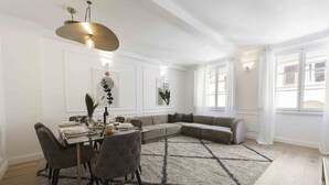 A dining area with a table set for four, a sofa, and a large rug.