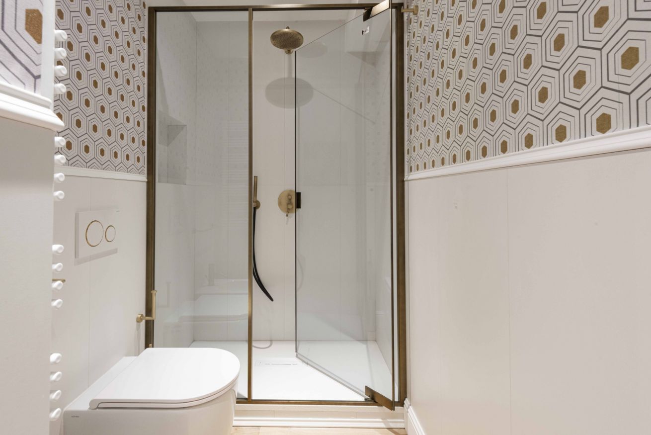 A modern bathroom with a glass-enclosed shower, a white toilet, and patterned wall tiles.