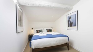 A bedroom with a bed, pillows, a nightstand, a framed picture, and a ceiling with exposed beams. - LVL2 By MMega Homes & Villas (Firenze)