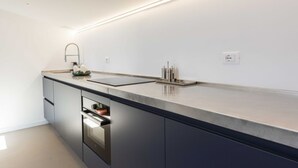 A modern kitchen with a built-in oven, a stainless steel sink, and a countertop. - LVL2 By MMega Homes & Villas (Firenze)