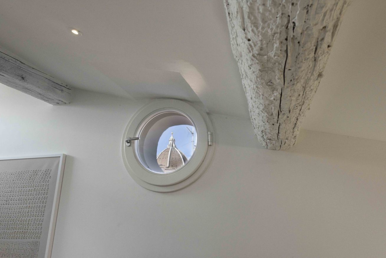 A room with a skylight, a wooden beam, and a textured wall.