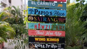 Un panneau indicateur portant divers noms de restaurants et d’établissements, notamment « Food Trucks », « El Carrito » et « Office & Parking ».
