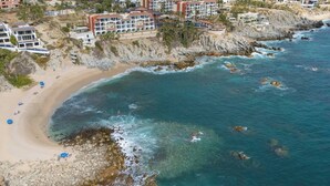 Un hôtel situé sur la côte, composé de plusieurs bâtiments, avec une plage de sable et des falaises rocheuses.