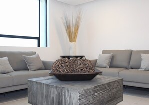 A modern living room with a grey sofa, a wooden coffee table, and a decorative vase with dried reeds. - Hangar Inn Tijuana (Tijuana)