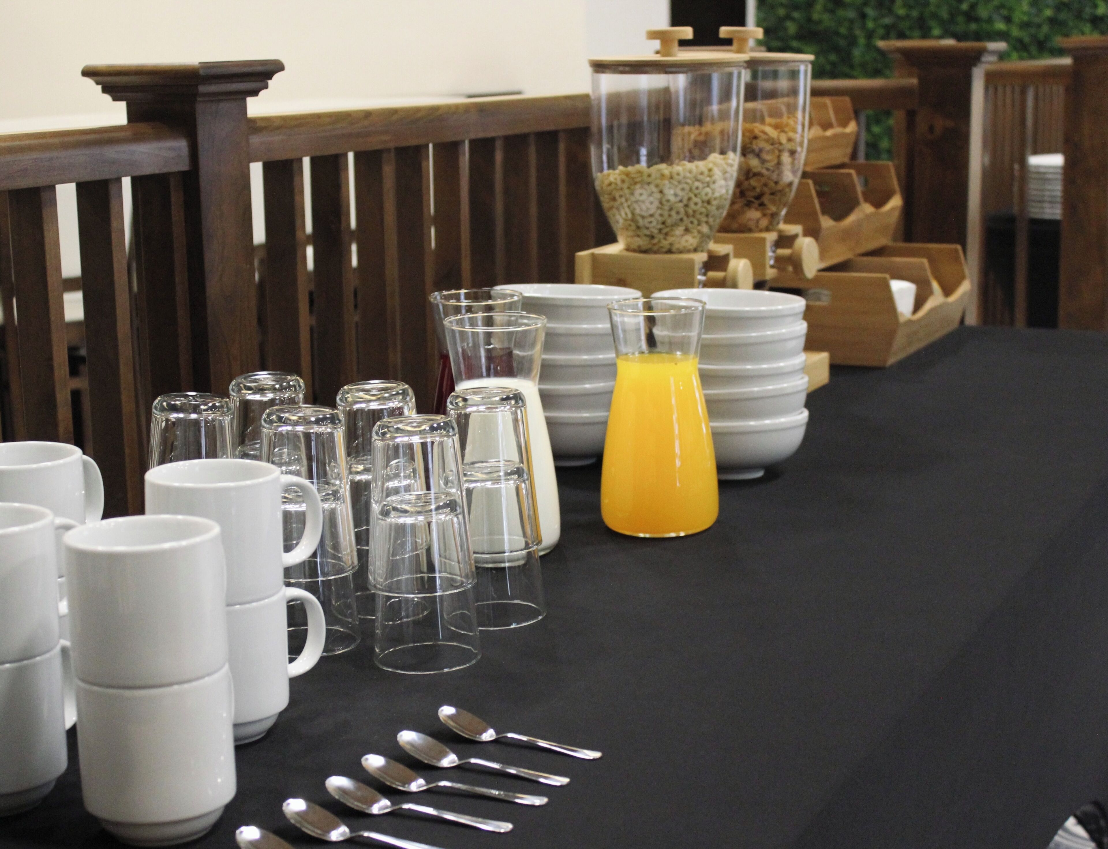 A breakfast table with white mugs, clear glasses, and a jug of orange juice.