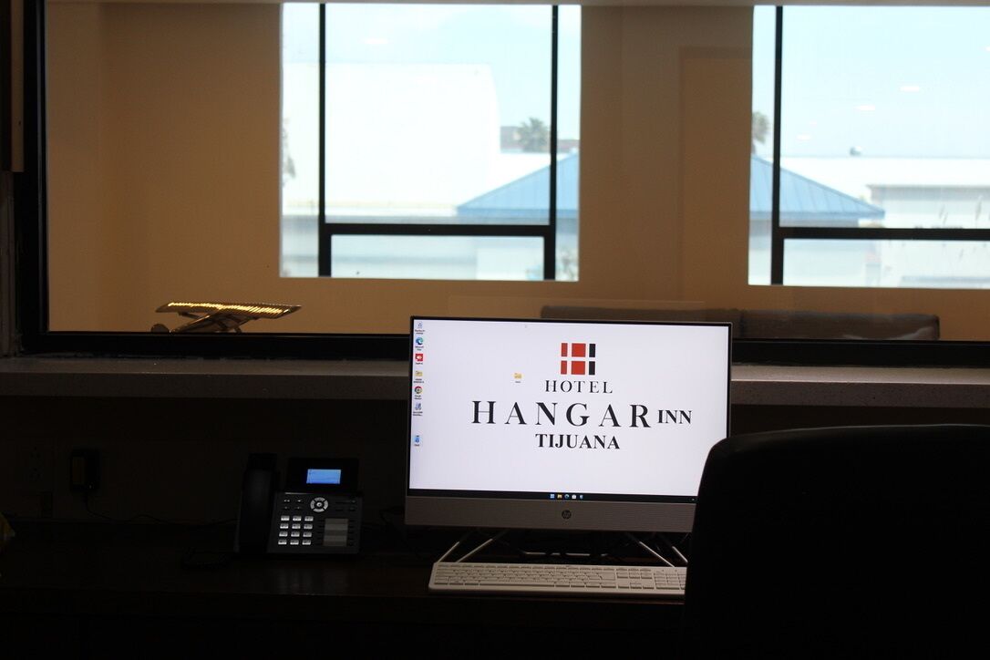 A hotel reception desk with a computer monitor displaying the hotel's name, a telephone, and a keyboard.