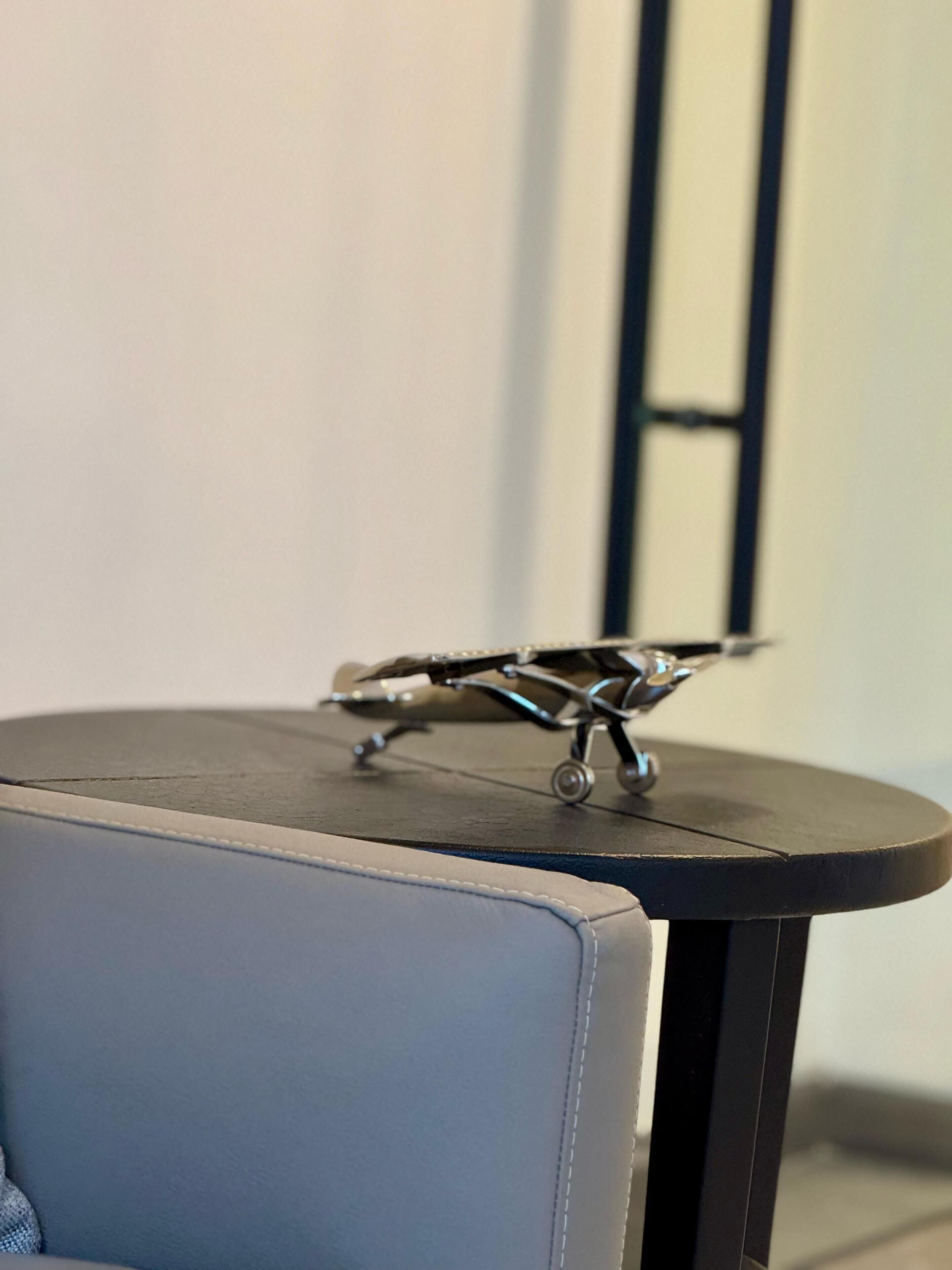Una pequeña mesa redonda con un modelo de avión metálico encima.