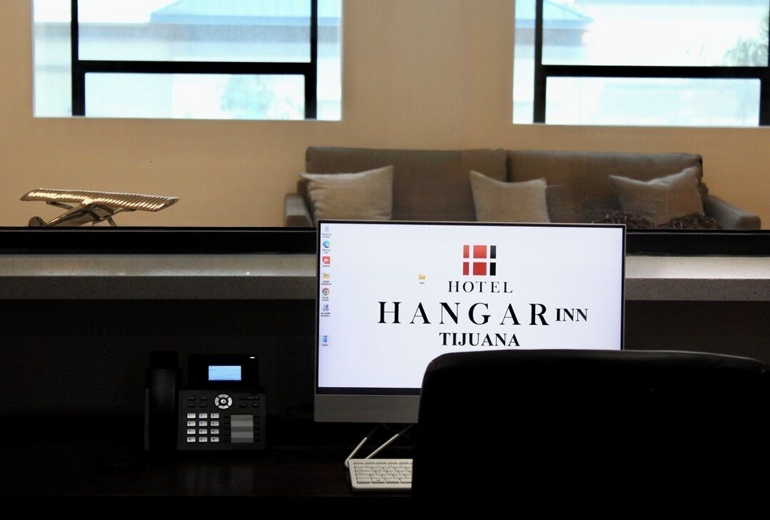 A reception desk with a computer monitor displaying the name "HOTEL HANGARIN TIJUANA".