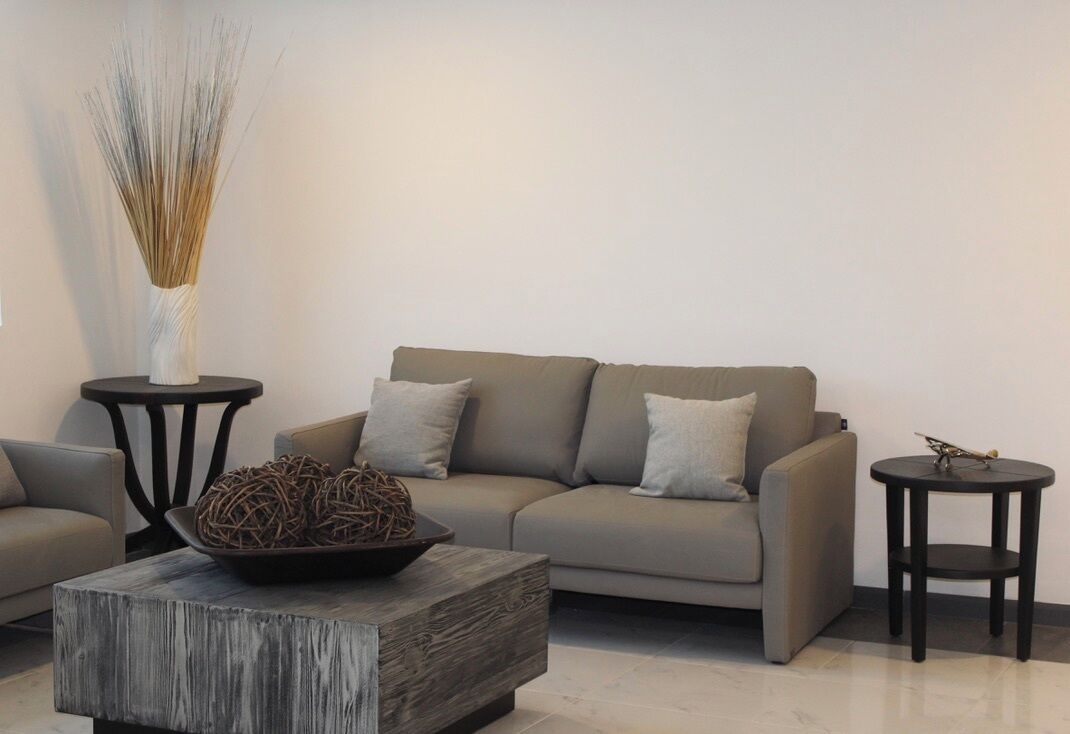 Una sala de estar moderna con un sofá, una mesa de centro y dos mesitas auxiliares.