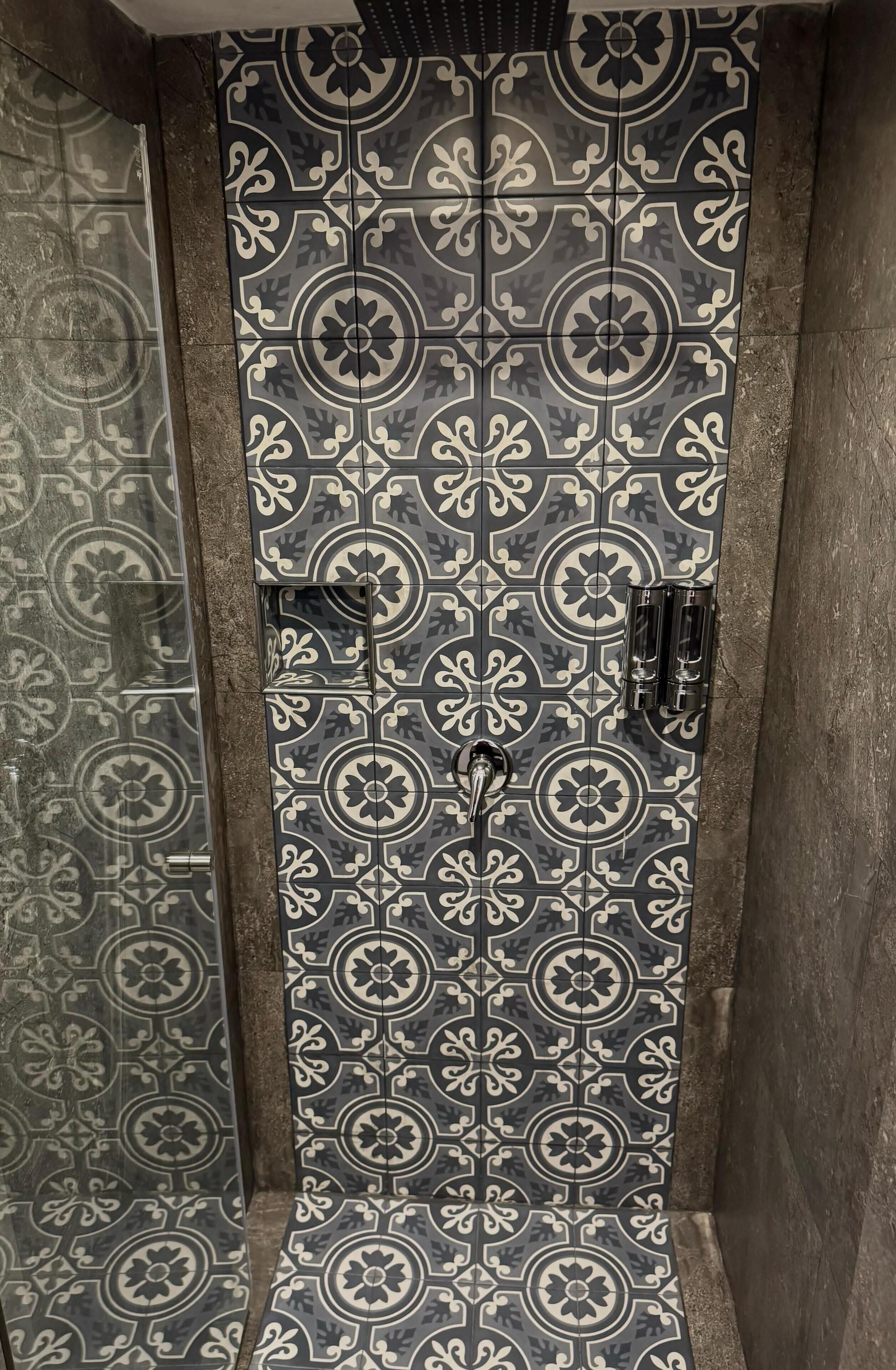 A shower area with patterned tiles and a glass door.
