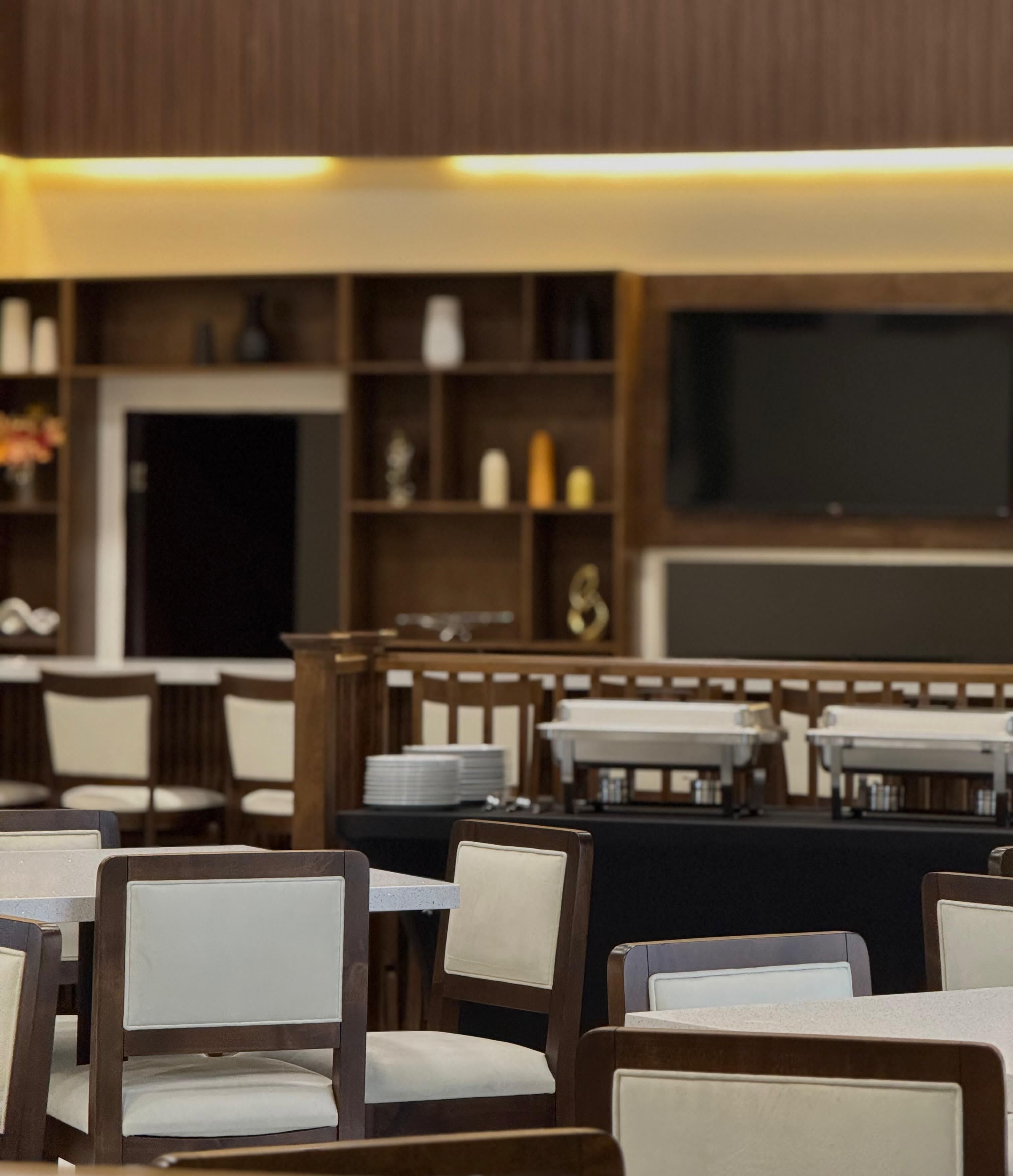 Un restaurante con mesas y sillas de madera, una pizarra y estantes con distintos objetos.