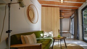 A modern living room with a green sofa, a round coffee table with a vase, a floor lamp, and a large window with curtains. - Espacio 1902 Sierra de Madrid (Collado Villalba)