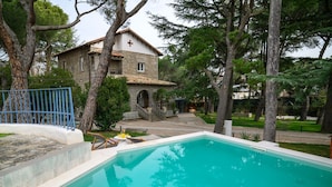 A swimming pool with a stone wall and a small table with chairs.