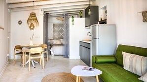 Un espace de vie compact comprenant un coin repas, un canapé vert et une petite cuisine.