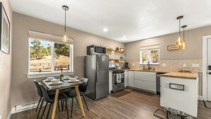 A modern kitchen with a dining area, wooden flooring, and a view of the outdoors. - LUX Guest Suite Near Amazing Hiking Trails (Colorado Springs)