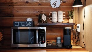 Una cocina con microondas, barra de café y refrigerador.