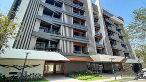 A multi-story building with a modern architectural design, featuring balconies and a central vertical structure.