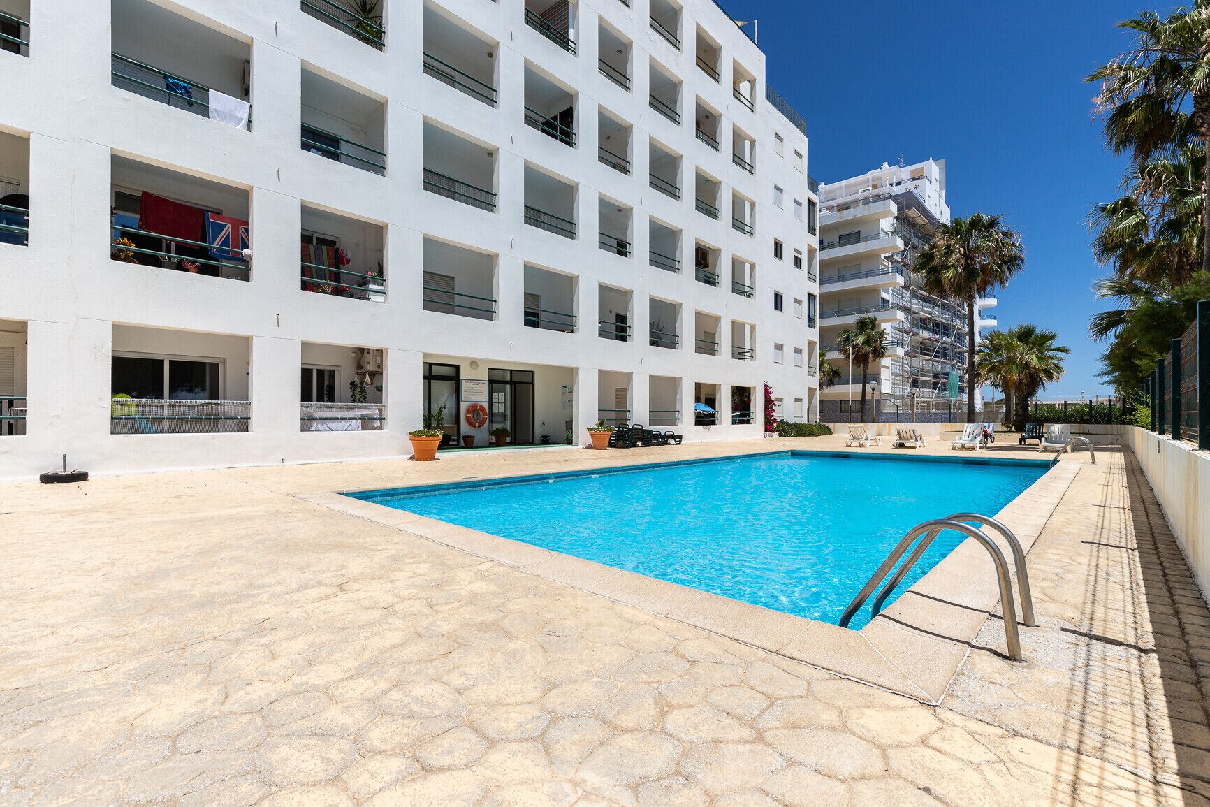 Un edificio moderno con piscina, area relax all'aperto e palme.