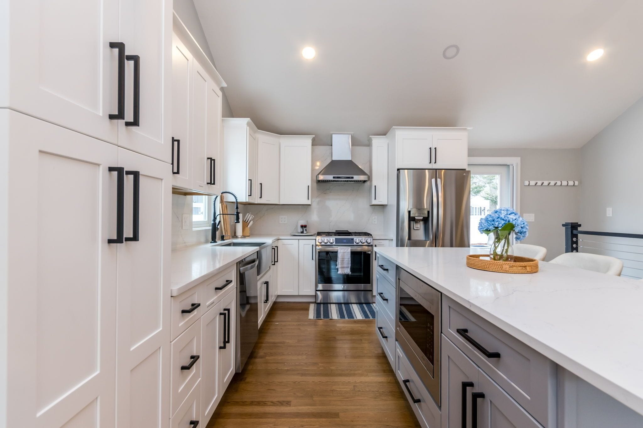 A modern kitchen with white cabinetry, stainless steel appliances, and a marble countertop.