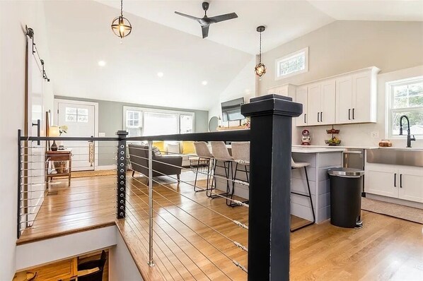 A spacious kitchen with white cabinets, a black countertop, and a wooden floor.