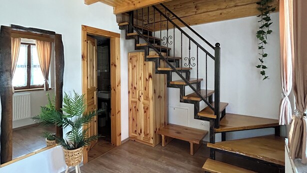 A wooden interior with a staircase, wooden walls, and a large mirror.