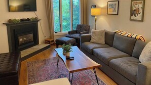 Una sala de estar con chimenea, un sofá, una mesa de centro y un televisor.