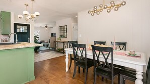 A modern kitchen with a central island, wooden flooring, and a dining area with a white table and dark chairs.