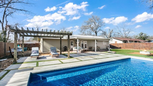A backyard with a swimming pool, patio furniture, and a pergola.