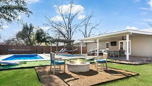 A backyard with a swimming pool, a fire pit, and outdoor seating.