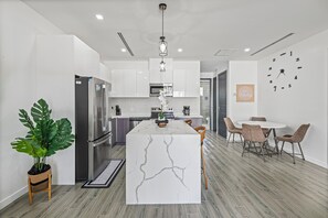 Une cuisine moderne dotée d’un îlot central, d’appareils électroménagers en acier inoxydable et d’un coin repas avec des chaises.