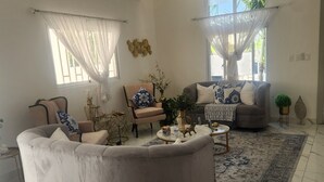 A living room with a curved sofa, a round coffee table, and a patterned rug. - Welcome  to Villa Julesmi  (La Romana)