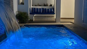 A swimming pool with a waterfall feature, a covered seating area, and a ceiling fan. - Welcome  to Villa Julesmi  (La Romana)