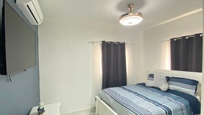 A bedroom with a bed, curtains, a ceiling fan, and a wall-mounted air conditioner. - Welcome  to Villa Julesmi  (La Romana)
