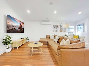A modern living room with a sectional sofa, a round coffee table, and a large painting on the wall.