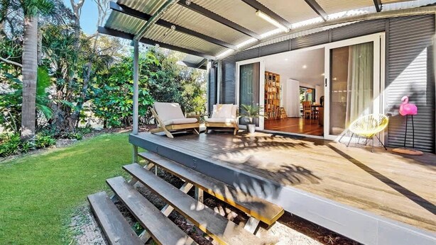 Une maison moderne dotée d’un patio couvert, d’un espace salon extérieur et offrant une vue sur l’intérieur.