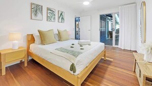 Une chambre avec un lit en bois, des murs blancs et un plancher en bois.