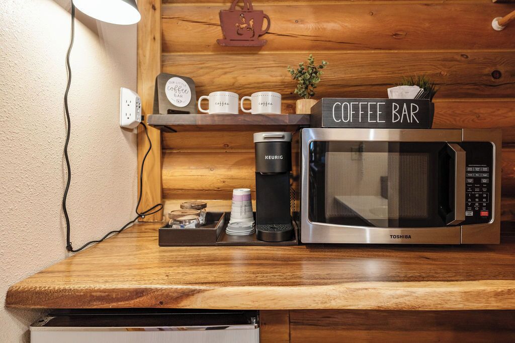 A kitchen counter with a coffee maker, a microwave, and a coffee bar sign.