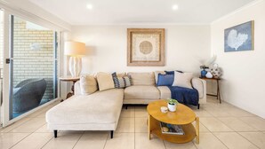 A modern living room with a sectional sofa, a round coffee table, and a framed artwork on the wall.
