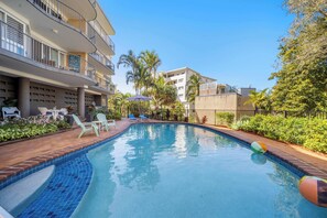 A swimming pool with lounge chairs and a palm tree in the background.