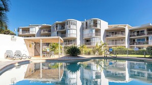 A hotel with a swimming pool, multiple balconies, and a covered outdoor seating area. - Surfside Beachfront 3bed Apt - Direct Beach Access (Buddina)