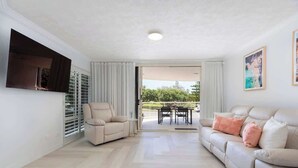 A spacious living room with a sofa, armchair, and a dining table.