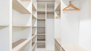 A walk-in closet with multiple shelves and a wooden hanger on the wall.