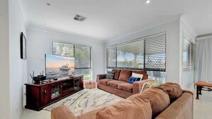 Una sala de estar con un televisor de pantalla plana grande, un sofá marrón y un mueble de madera para entretenimiento.
