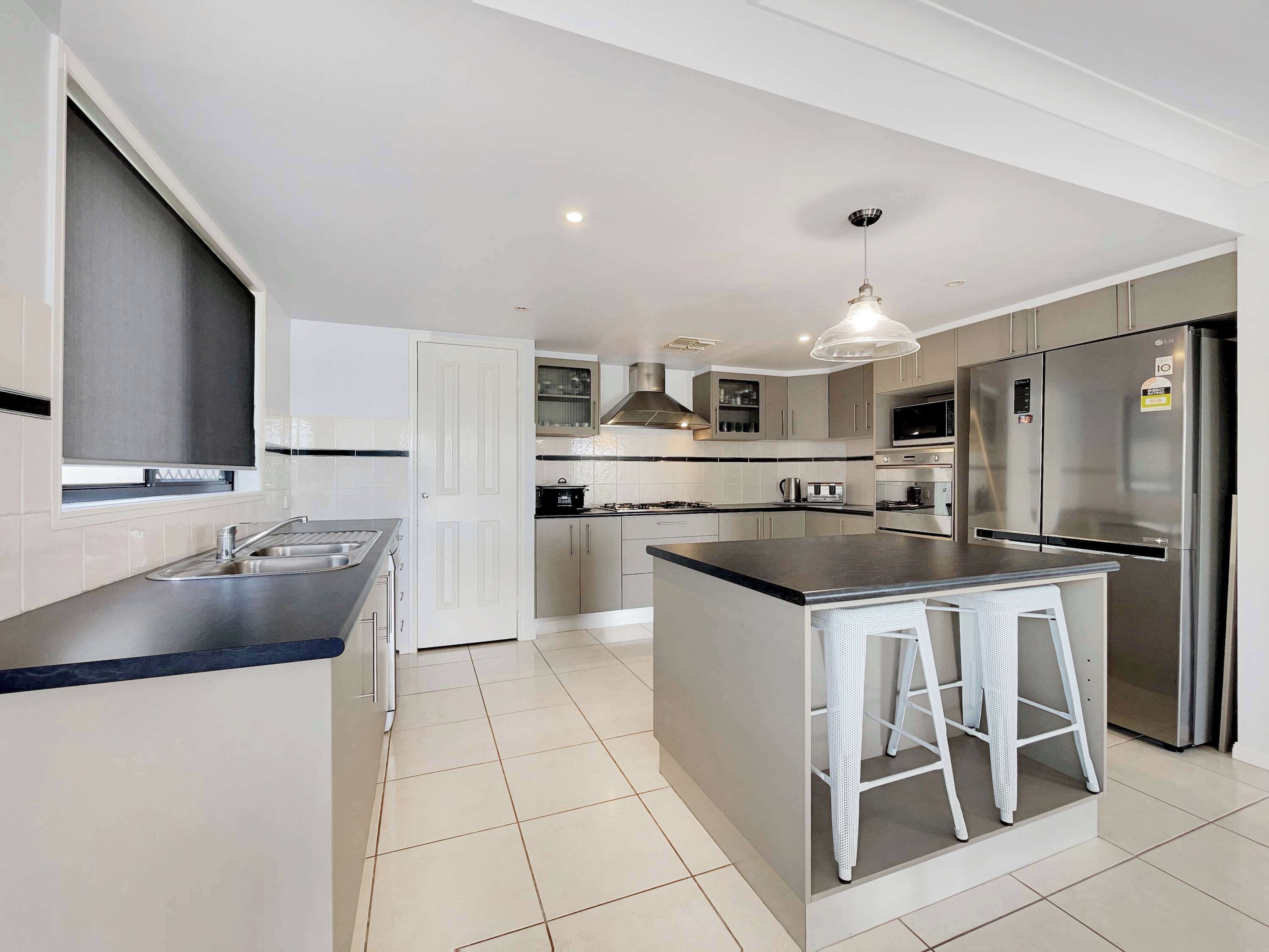 A modern kitchen with a central island, stainless steel appliances, and a pendant light.