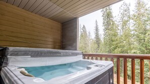 A hot tub on a wooden deck with a view of trees.